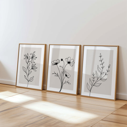 Minimalist floral line art posters in wooden frames on a modern wood floor