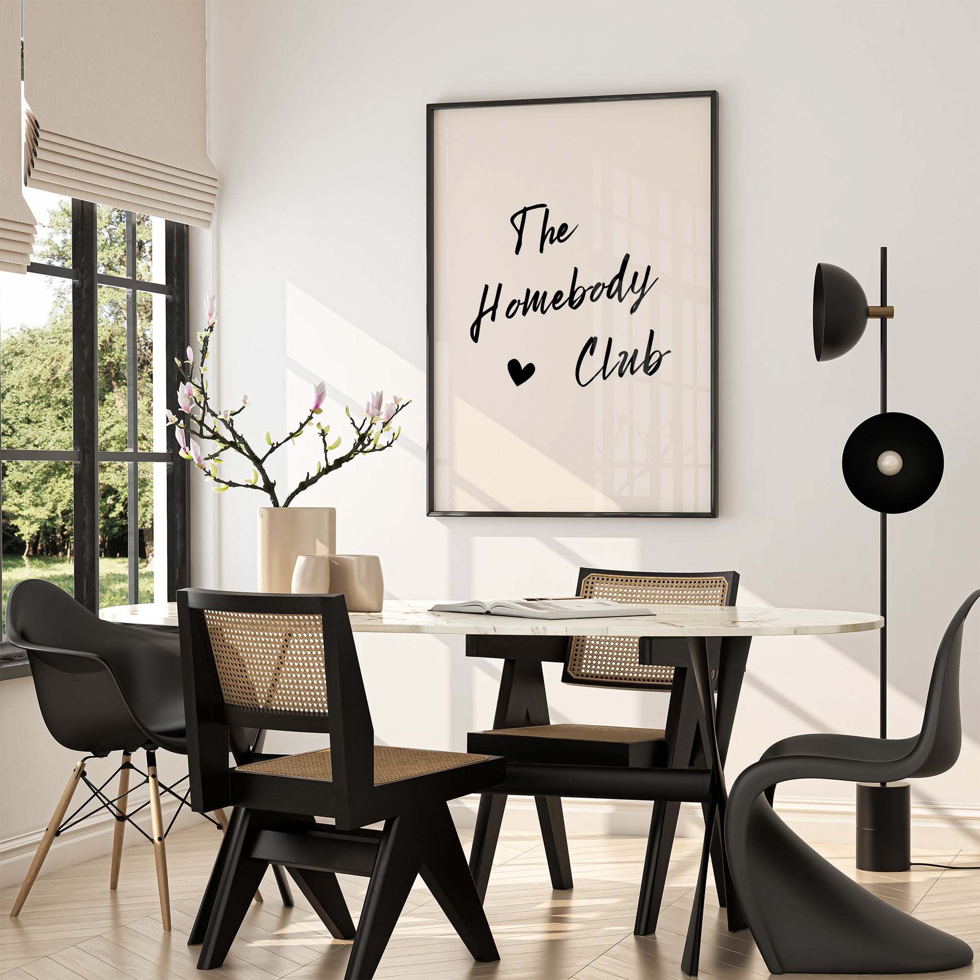 Dining room with black chairs, a white table, and a framed poster on the wall.