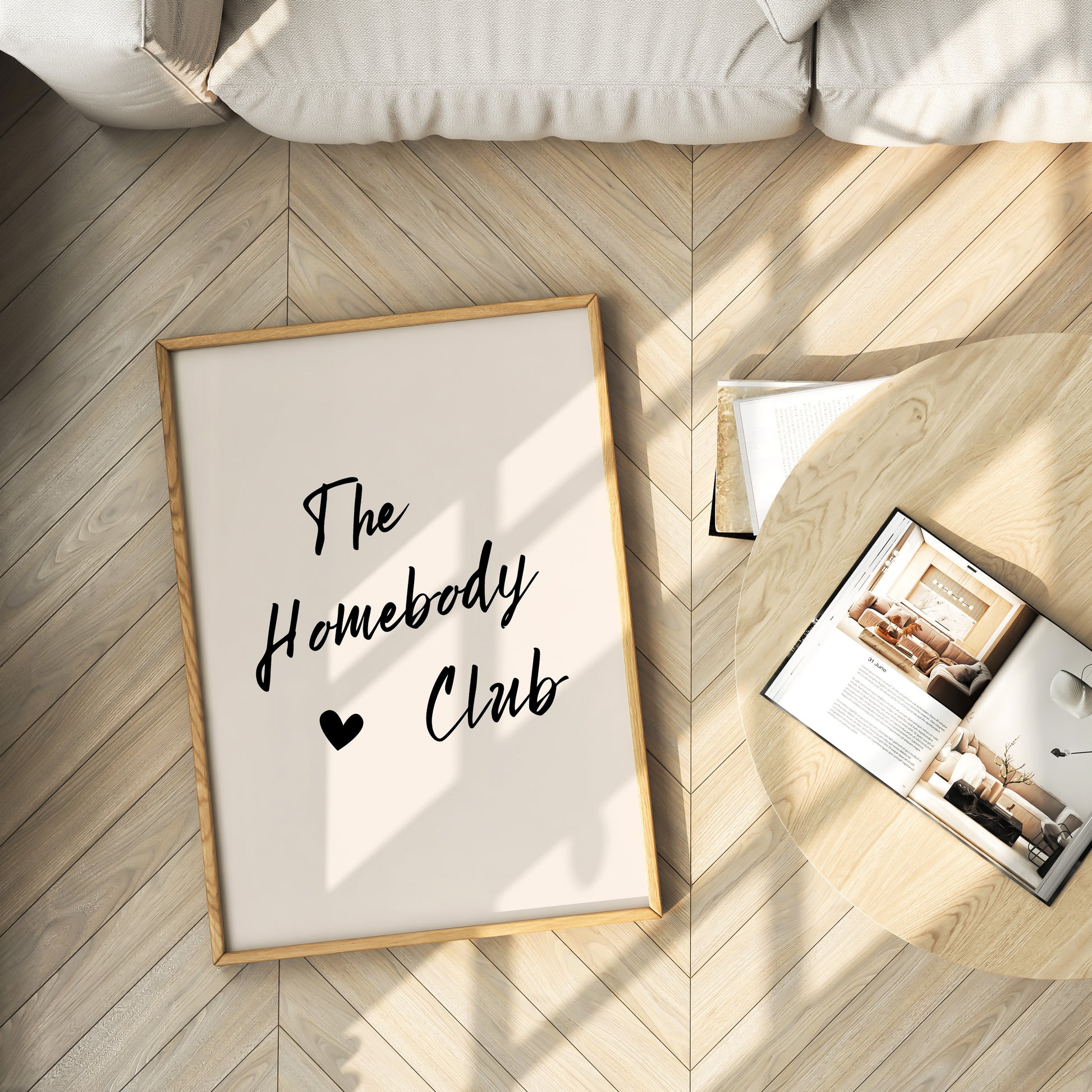 Framed print with 'The Homebody Club' text on a wooden floor.